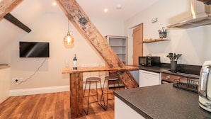 Una cucina con una scala in legno, un angolo bar, una TV ed elettrodomestici moderni.