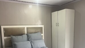 Ein Schlafzimmer mit einem Bett, einem Kleiderschrank und einem Kopfteil mit strukturierter Gestaltung.