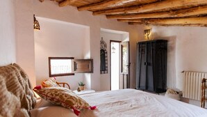 A bedroom with a large bed, a wooden ceiling, a wardrobe, and a window. - Finca El Almendrillo (AN)