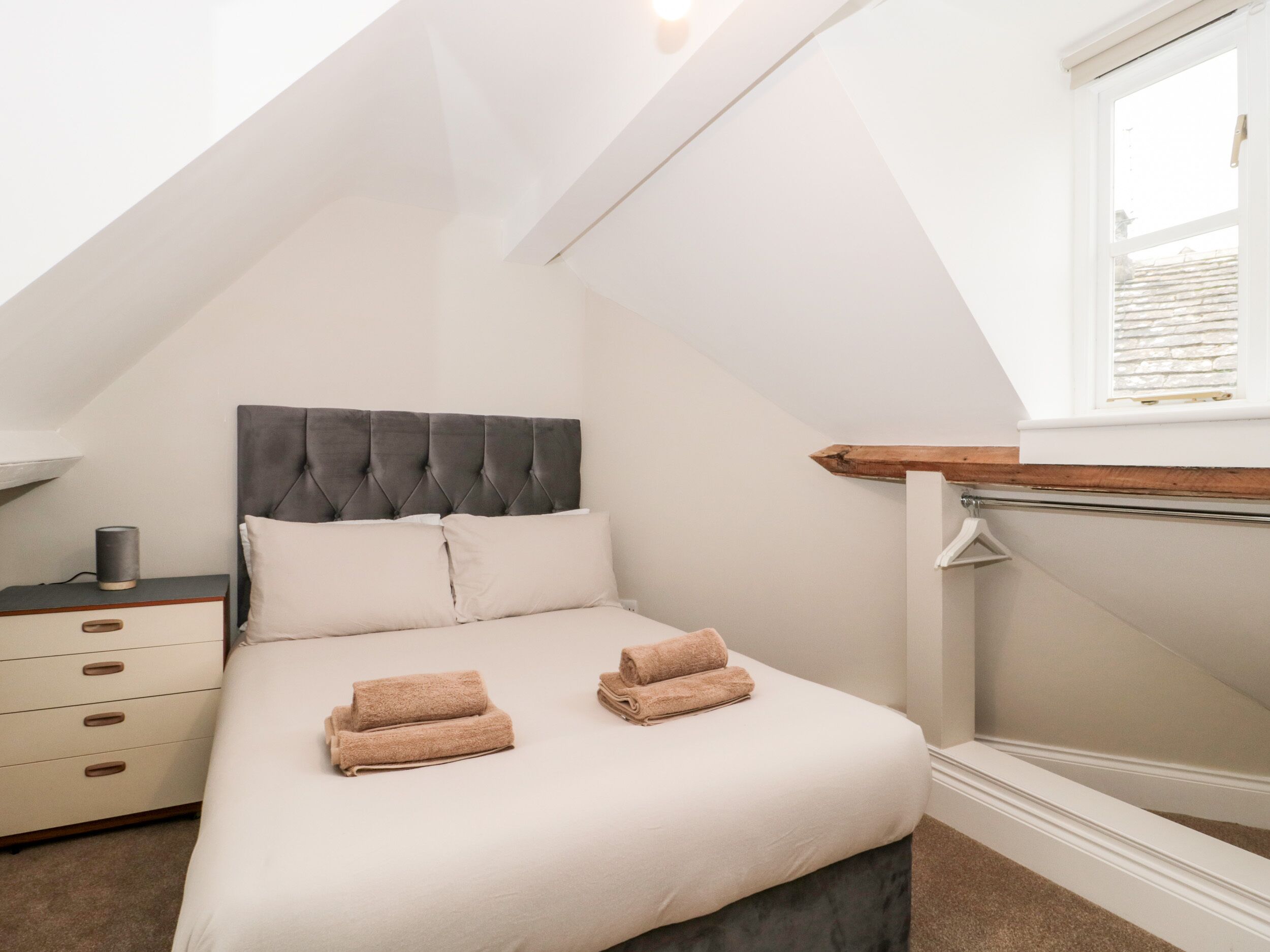 A bedroom with a bed, bedside table, and a window.