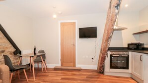 Una cocina compacta con puerta de madera, televisor de pantalla plana y microondas.