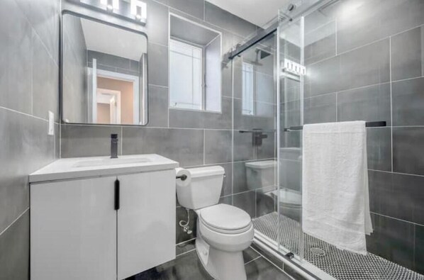 A modern bathroom with a toilet, sink, and shower area. - The Eden - Beachfront (Long Beach)