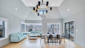 A spacious living area with a light blue sofa, a dining table with chairs, and a modern chandelier. - Villa Paraiso (Long Beach)