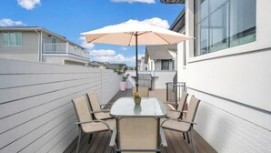 A patio with a glass table and four chairs, an umbrella, and a potted plant. - Villa Paraiso (Long Beach)