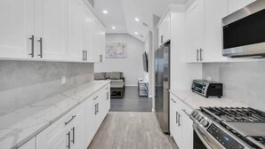 A modern kitchen with white cabinetry, a built-in oven, and a microwave.