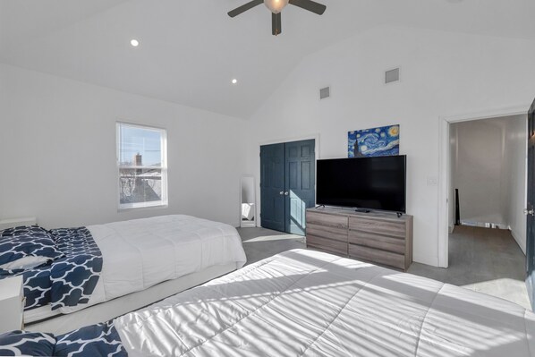 A modern bedroom with a large bed, a TV, and a wardrobe.