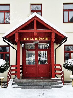 A red-brick building with a snow-covered roof and a sign reading 'HOTEL BRANIK.' - Hotel Braník (Prague)