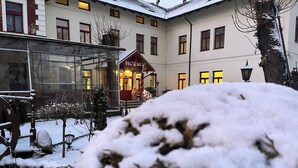 Un cortile innevato con un edificio dalle molte finestre e un ingresso ben visibile.
