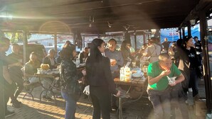 Un'area pranzo all'aperto con tavoli e sedie, persone che mangiano e socializzano.