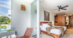 A modern bedroom with a large bed, a ceiling fan, and a view of a swimming pool. - NHOA 211B Lux 1BR Condo Pool View in Aldea Zama (Tulum)