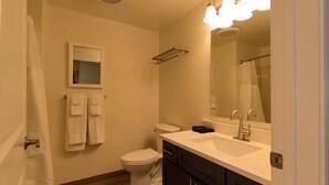 A bathroom with a toilet, sink, mirror, and towel rack. - Suites  On  Mass  -  C3 (Lawrence)