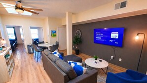 A modern living room with a sofa, a round coffee table, and a TV mounted on the wall. - Suites  On  Mass  -  C3 (Lawrence)