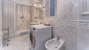 Bathroom features a washing machine, bidet, and shower with glass enclosure.