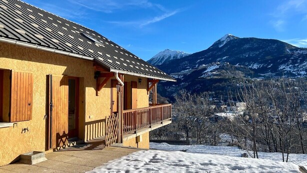 Un chalé con balcón que da a un paisaje montañoso nevado.