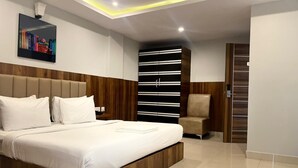 Un dormitorio moderno con una cama grande, cabecera de madera, una estantería y una silla.