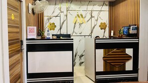 Zona de recepción con paredes de mármol, paneles de madera y un mostrador con computadora y un código QR para servicios a los huéspedes.