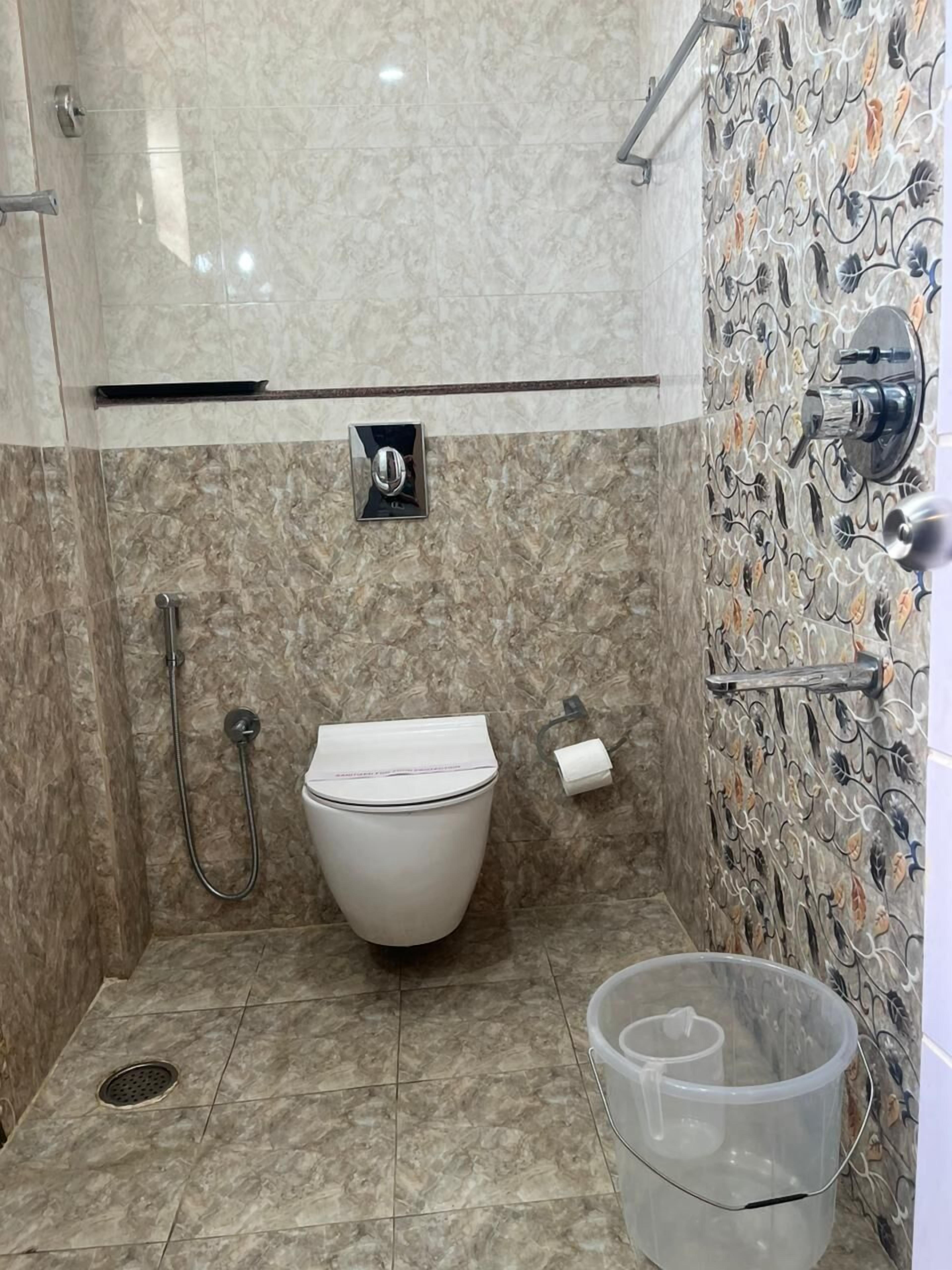 Kylpyhuone, jossa on wc, suihku ja koristeellinen laattaseinä.
