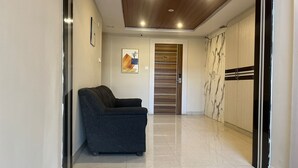 Un pasillo con un sofá de color oscuro, una puerta de madera y un armario con diseño a rayas.