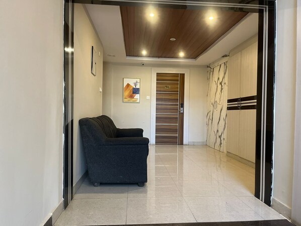 A hallway with a dark-colored sofa, a wooden door, and a wardrobe with a striped design.
