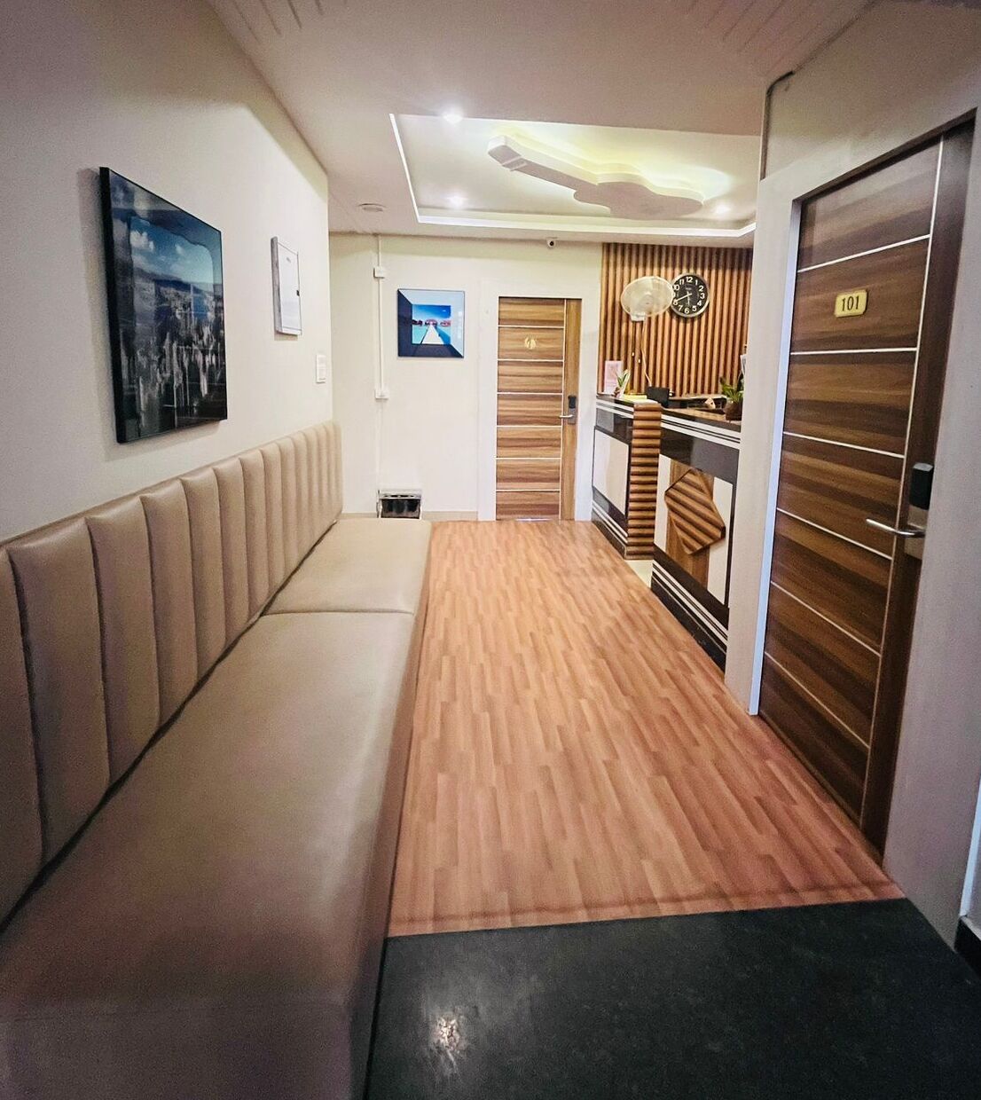 A hallway with a wooden floor, a bench, and a door with a number sign.