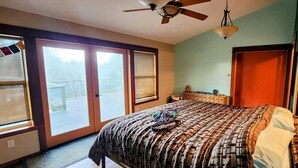 Ein Schlafzimmer mit Bett, Deckenventilator, Schminktisch und Fenster mit Blick.