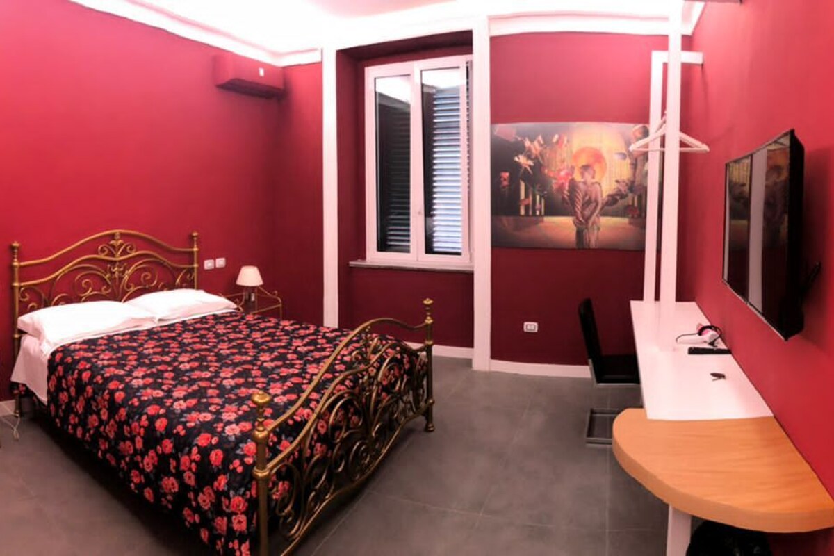 Ein Zimmer mit Bett, Nachttisch, Spiegel, Dusche und Toilette.