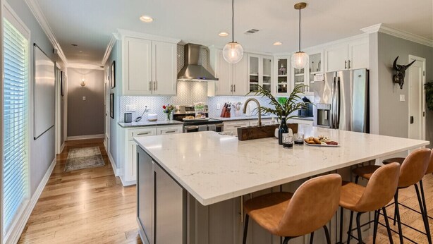 A modern kitchen with white cabinets, a large island, and pendant lighting. - Tesla Charger/Gorgeous Inside/Walk to Restaurants (Austin)