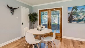 A dining area with a round table, white chairs, a bull skull decoration, a potted plant, and a painting on the wall. - Tesla Charger/Gorgeous Inside/Walk to Restaurants (Austin)