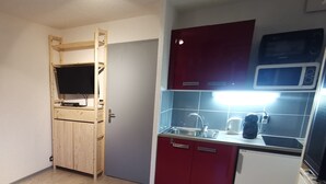 Una cocina compacta con un mueble de madera, un microondas integrado y un lavamanos.