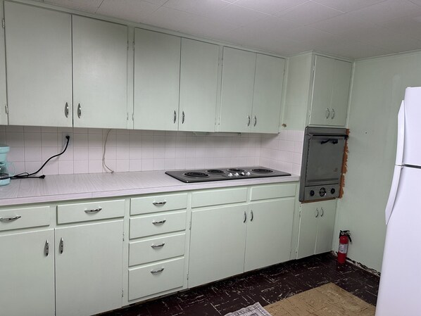 A kitchen with white cabinets, a stove, and a refrigerator.