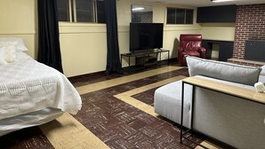 Ein Hotelzimmer mit einem Bett, einer Couch, einem Fernseher und einer Backsteinwand.