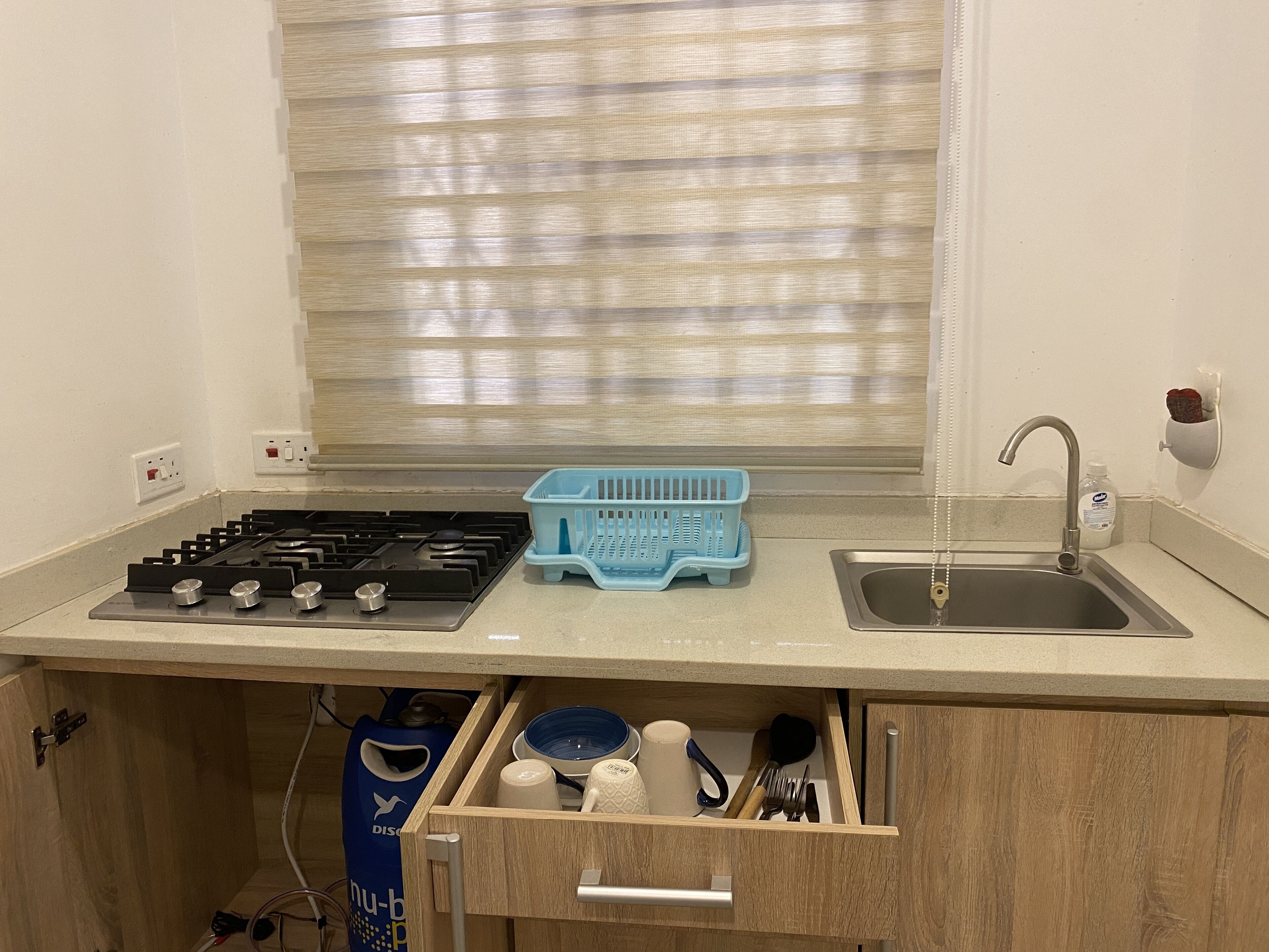 A kitchen with a gas stove, sink, and a blue dish rack.