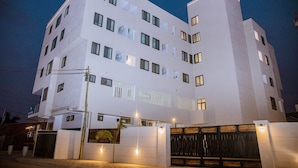 A multi-story building with a white facade, multiple windows, and a gated entrance. - Mayama Residences  (Accra)