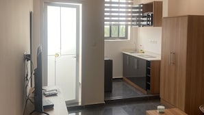 A modern kitchen with wooden cabinets, a countertop, and a built-in oven. - Mayama Residences  (Accra)