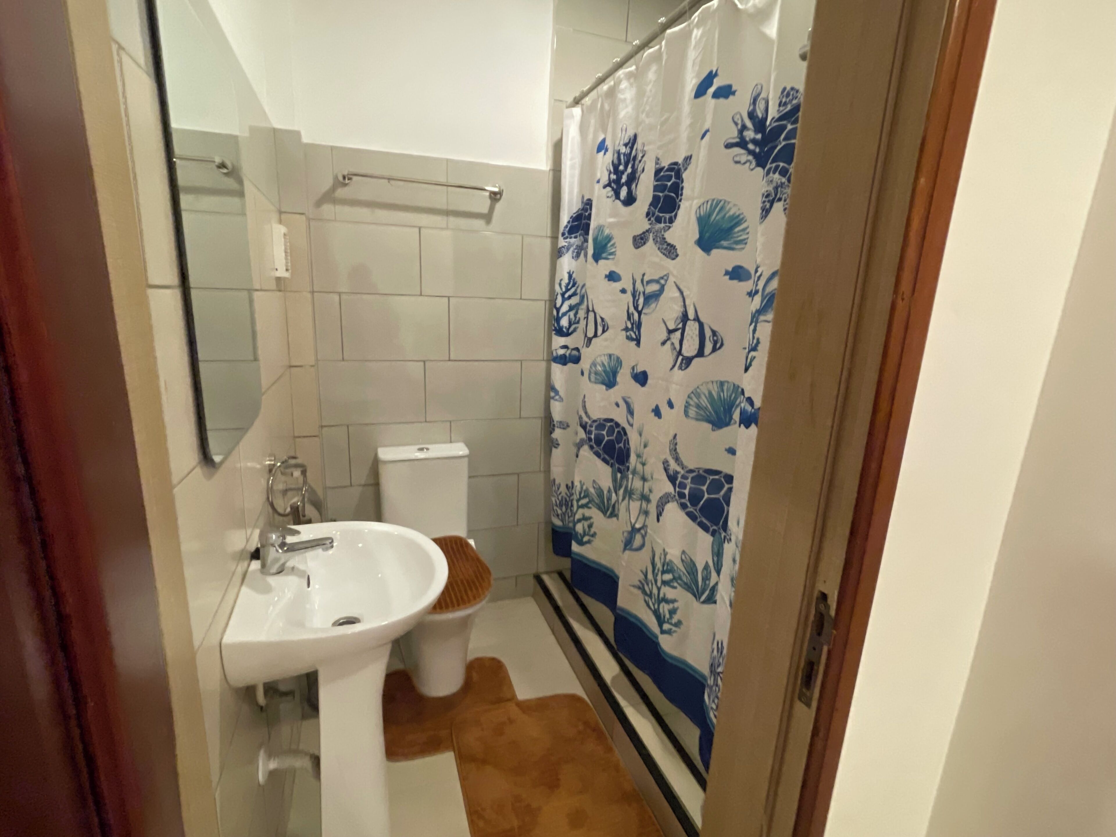 A bathroom with a white sink, a toilet, and a shower curtain with marine life patterns.