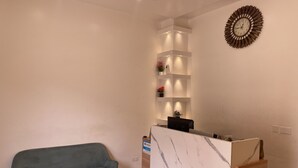 A reception area with a marble counter, a blue sofa, and a decorative wall clock. - Mayama Residences  (Accra)