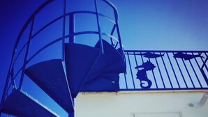 A spiral staircase leading to a balcony with a railing. - Beachfront villa in Fiumicino, terrace & sunset (Isola Sacra)
