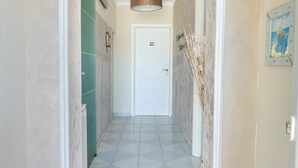 A hallway with a white door at the end, a green door to the left, and a framed picture on the right wall. - Beachfront villa in Fiumicino, terrace & sunset (Isola Sacra)