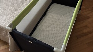 A bed with a wooden headboard, a bedside table with a clock, and a bedside lamp.