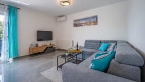 Una sala de estar moderna con un sofá gris, una mesa de centro, un televisor de pantalla plana y un cuadro en la pared.