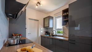 Una cocina moderna con estufa integrada, tabla de madera con pan y una ventana con vistas a la vegetación.
