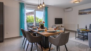 Un comedor moderno con una mesa de madera, sillas grises y una araña.