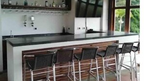 A modern kitchen with a bar area, equipped with bar stools and a large screen. - Casa Maria, Lagoon Calima (Club Las Anonimos)