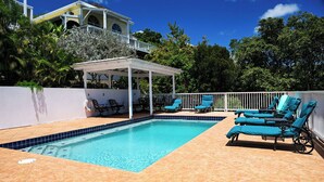 Una piscina con lettini e una zona patio coperta.
