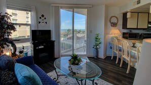 Un salon avec une table basse en verre, un canapé, un téléviseur et une vue sur le balcon.