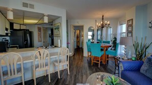 Une cuisine moderne équipée d’un réfrigérateur, un coin repas avec des chaises et un salon avec un canapé et une table basse.