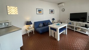 Een knus woongedeelte met een bank, een salontafel, een televisie en een magnetron.