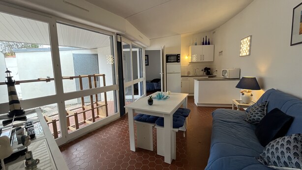 Een ruimtelijk ingerichte leefruimte met balkon, kitchenette, een eethoek en een zithoek met een bank en tafel.