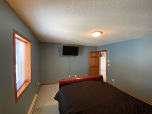 Cozy retreat with a single bed, flat-screen TV, and window with blinds.