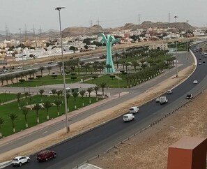A highway with multiple lanes, palm trees, and a distinctive green sculpture in the center.